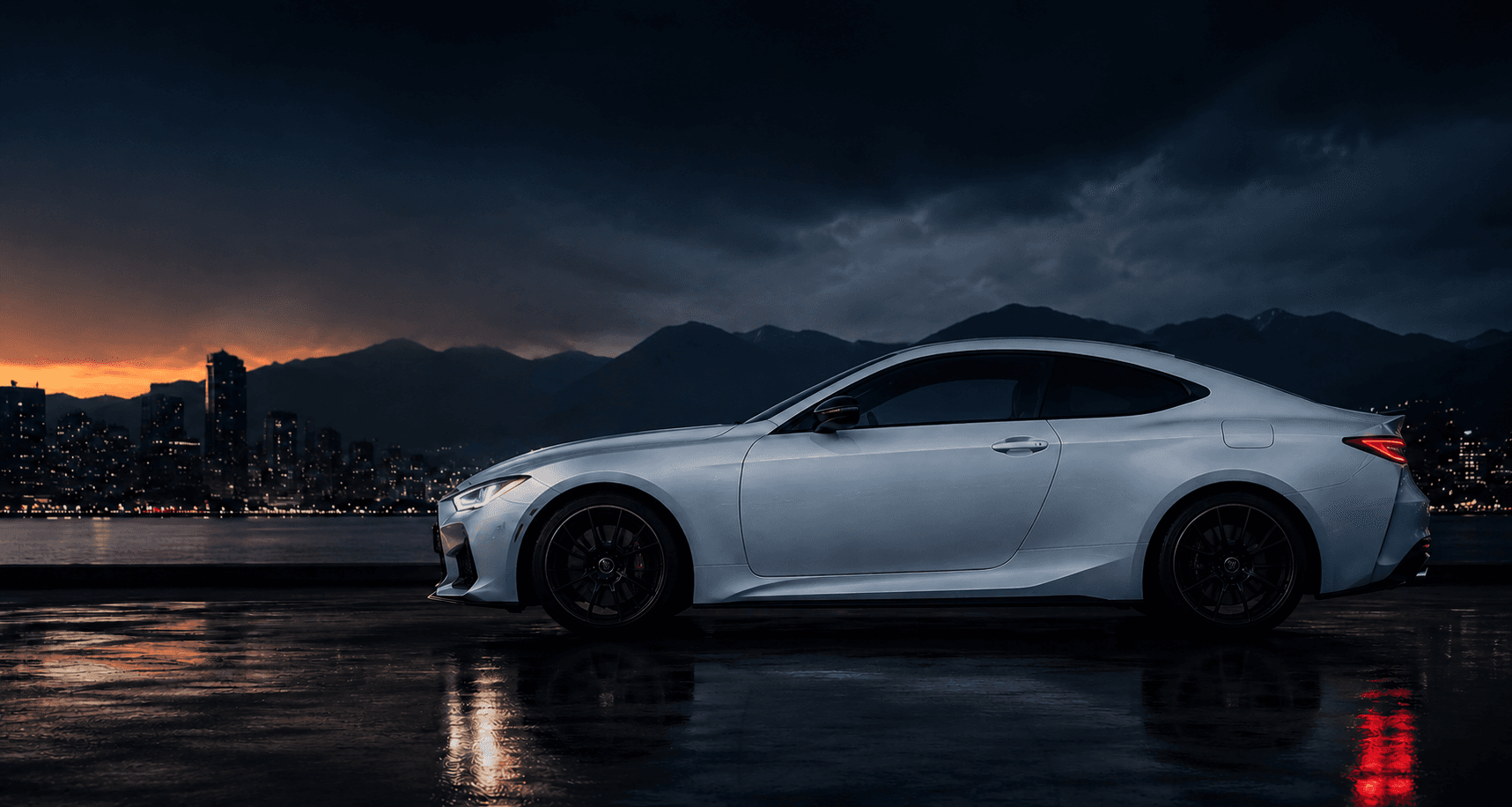 White sports car at dusk in front of the Vancouver skyline